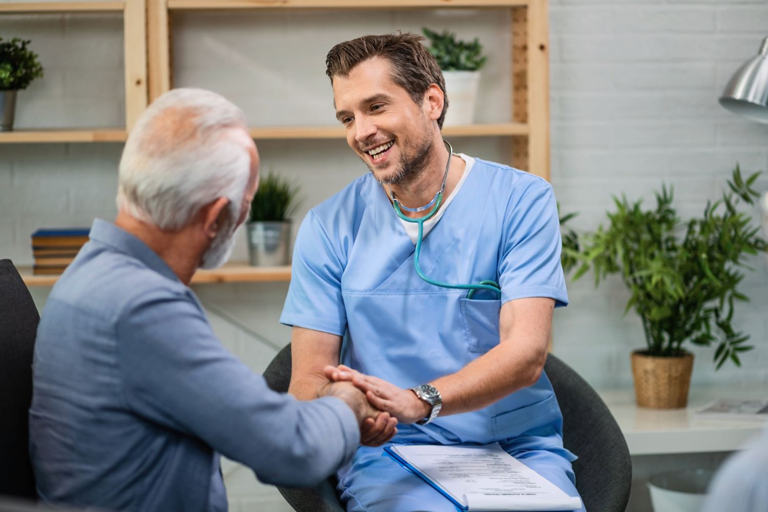 A doctor shaking hands with an older patient during a home visit